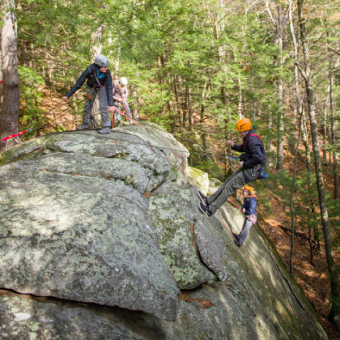 UNH 学生 climbing on a large rock