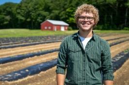 Eliudes营地Marcano, 来自波多黎各的交换生, stands in a field at the Kingman 研究 Farm, 去年夏天，他在那里帮助支持联合国大学的农业研究.